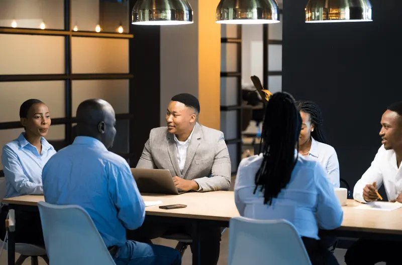 Six colleagues in a meeting at a long table.