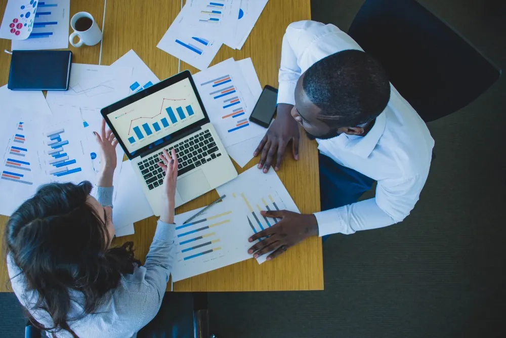 Seen from above: colleagues over printed charts and a laptop.